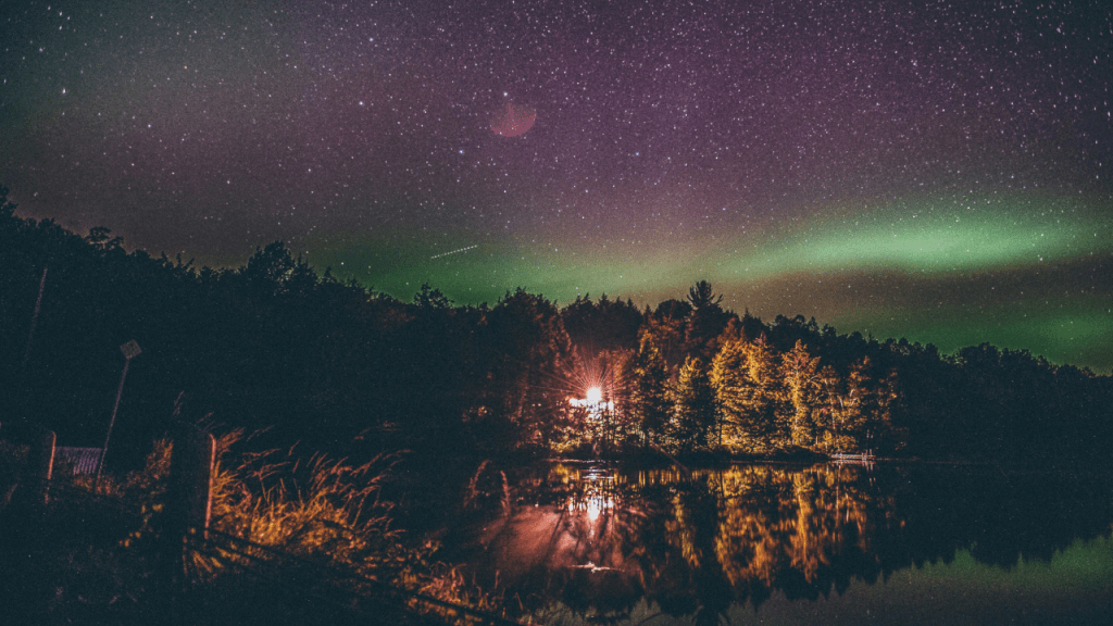 Aurora Borealis in a forest with a bright light under the stars